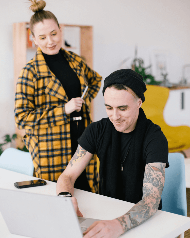 Two people looking at the laptops in the office